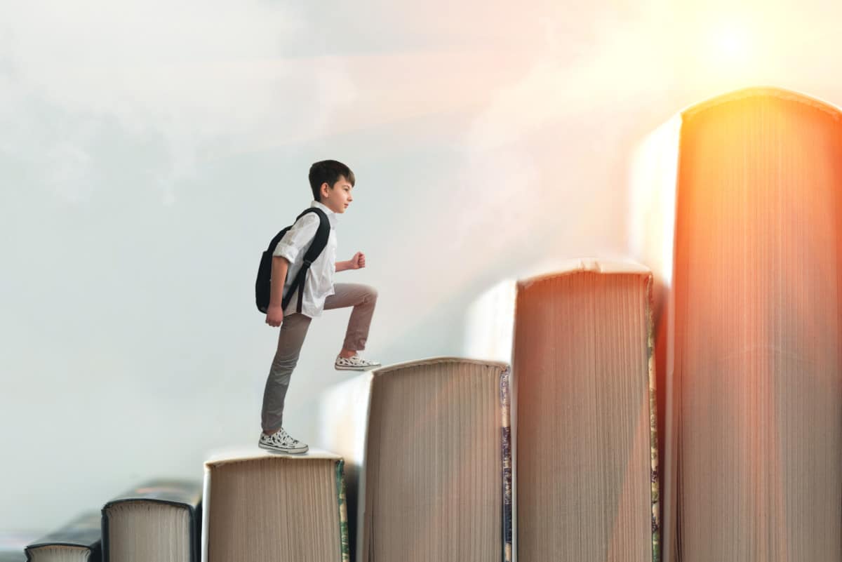 Child climbing stairs made of books